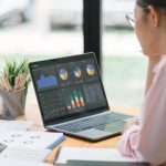 Marketing analyst working on a laptop in a cafe, planning campaign UTM tracking